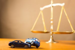 toy car crash in front of scales of justice