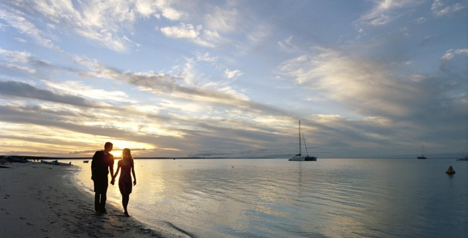 couple walking along beach during a pretty sunset