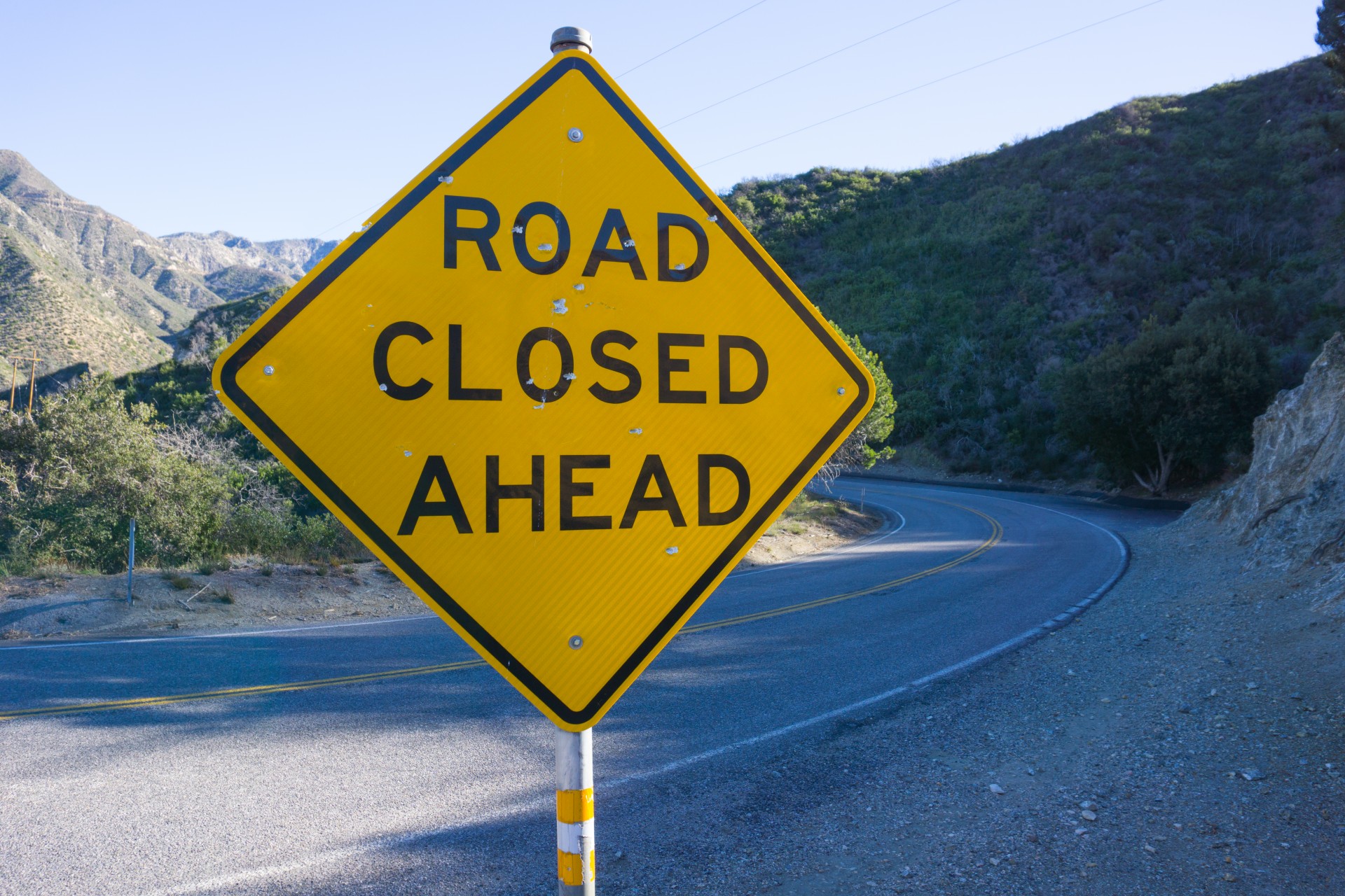 road closed ahead traffic sign on mountainous road