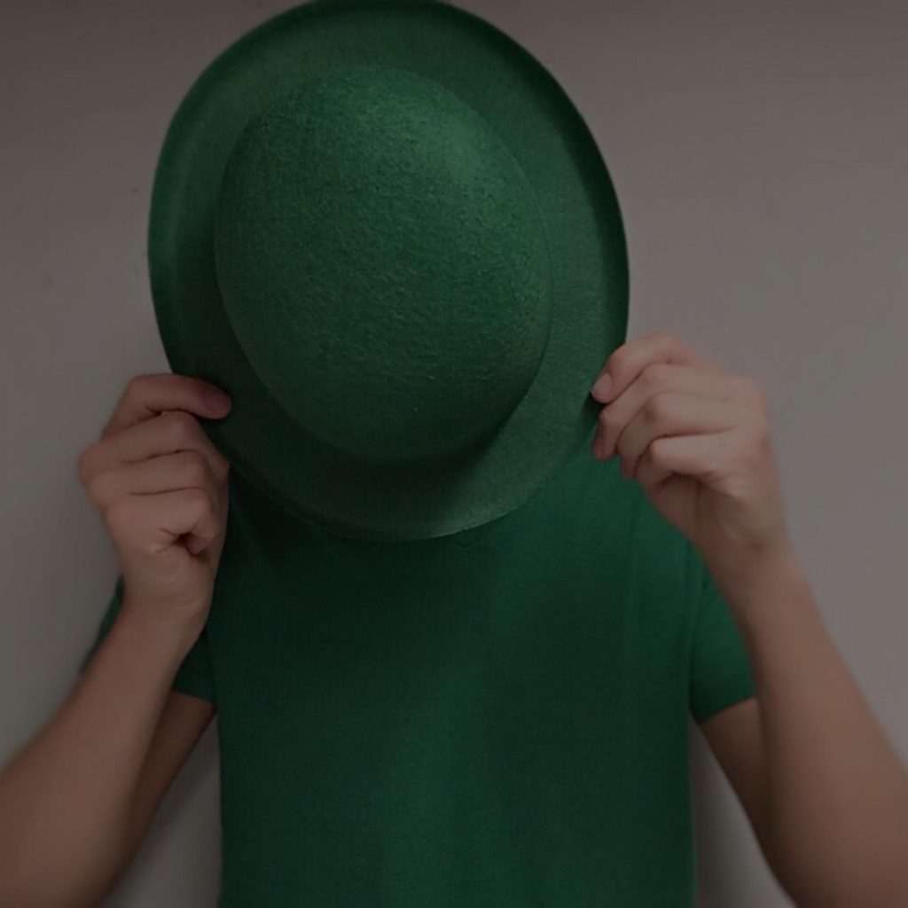 man in green shirt hiding behind green bowler hat on St. Patrick's Day
