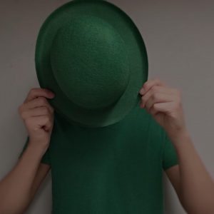 man in green shirt hiding behind green bowler hat on St. Patrick's Day