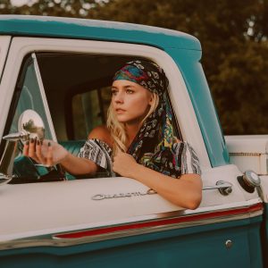 young girl in vintage pickup truck driver seat adjusting side view mirror