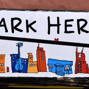 close up of park here sign with city drawings