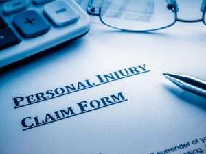 personal injury claim form with pen, glasses and calculator