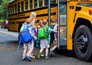group of five students getting on school bus