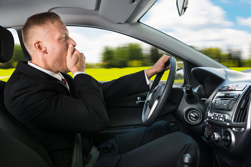tired man in business suit yawning as he drives