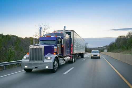 semi truck driving on highway next to passenger vehicle