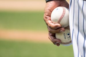 close up of baseball pitcher's hand with two baseballs