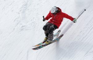 man in red jacket skiing down slope
