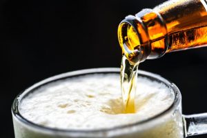 close up of beer being poured from bottle into glass