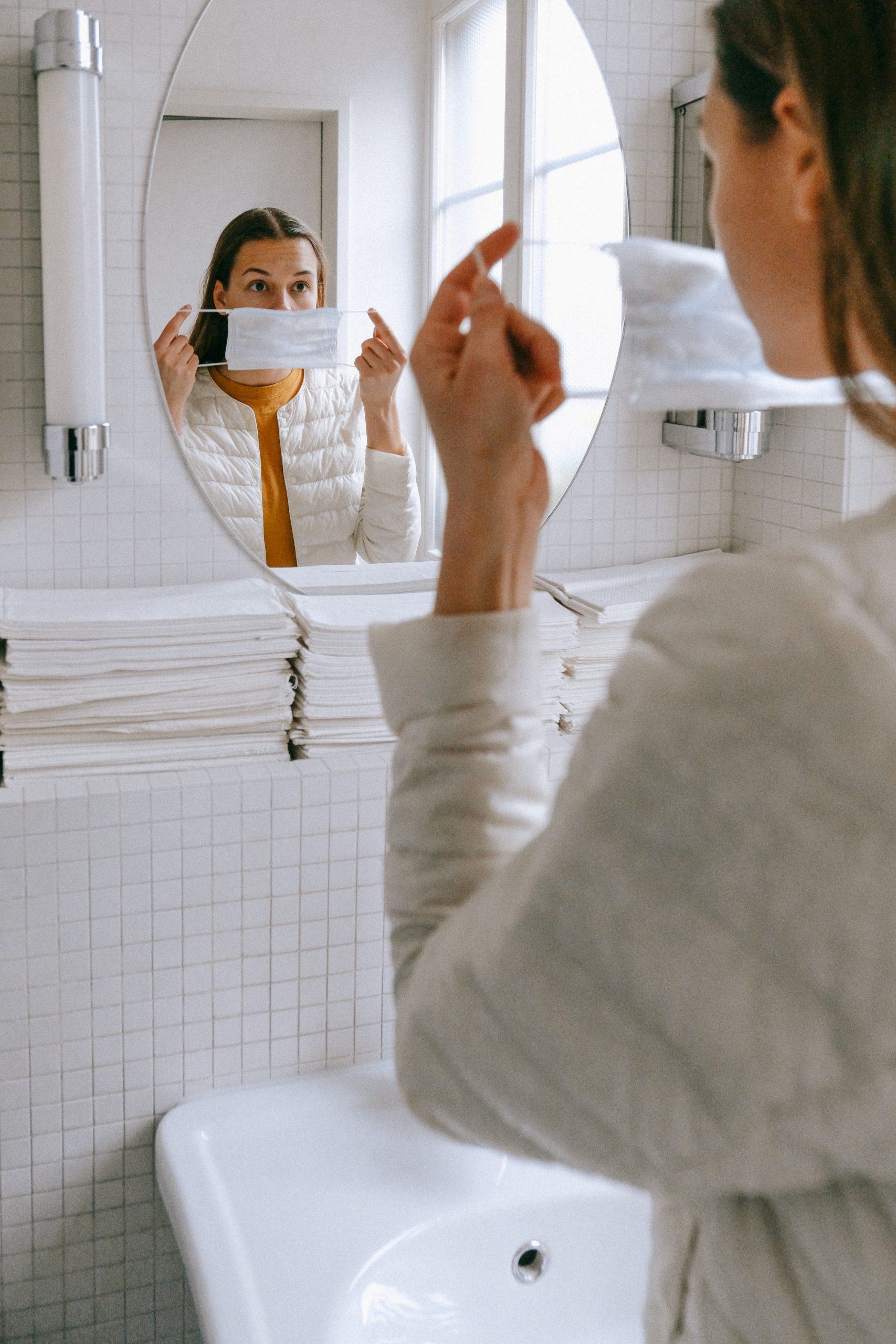 woman putting on a face mask in bathroom in front of mirror