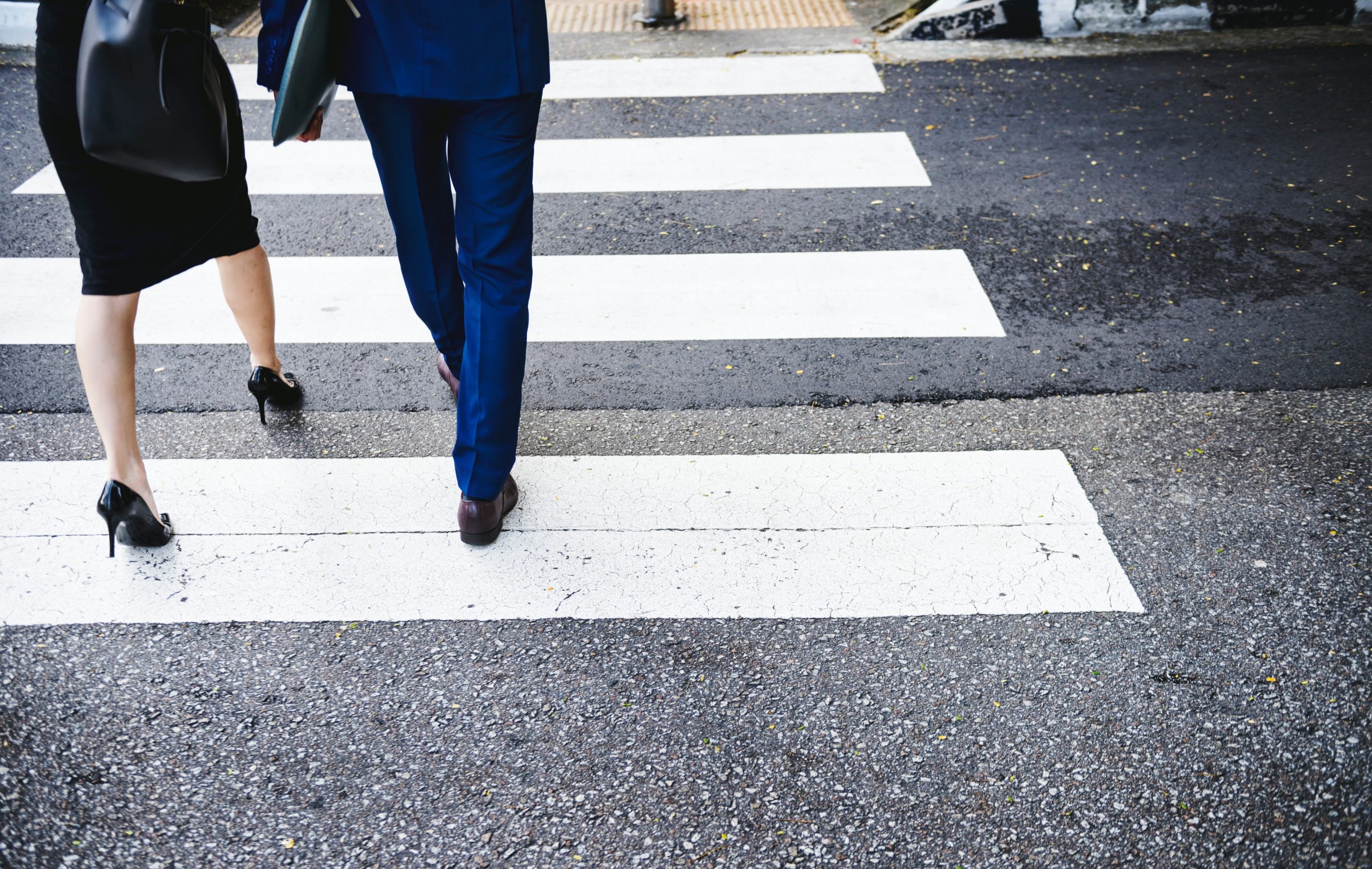 close up of man and woman pedestrians in formal dress crossing crosswalk