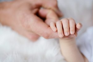 close up of baby holding parent's finger
