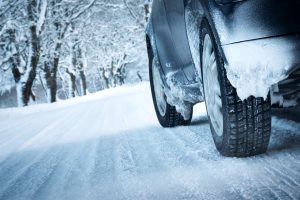 close up of car tires driving on snowy winter road