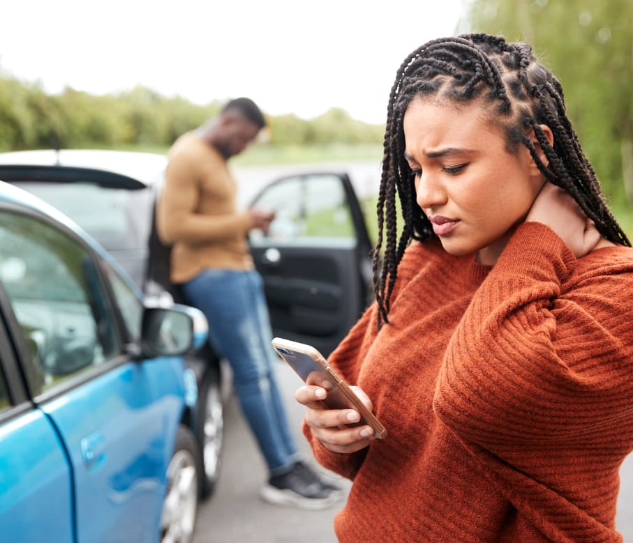 woman and man drivers on phones looking worried after car accident