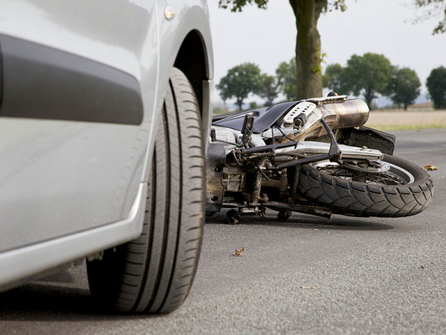 motorcycle laying on ground after accident with car