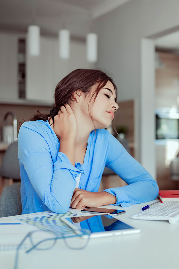 young woman seated at desk with back and neck pain after injury from accident