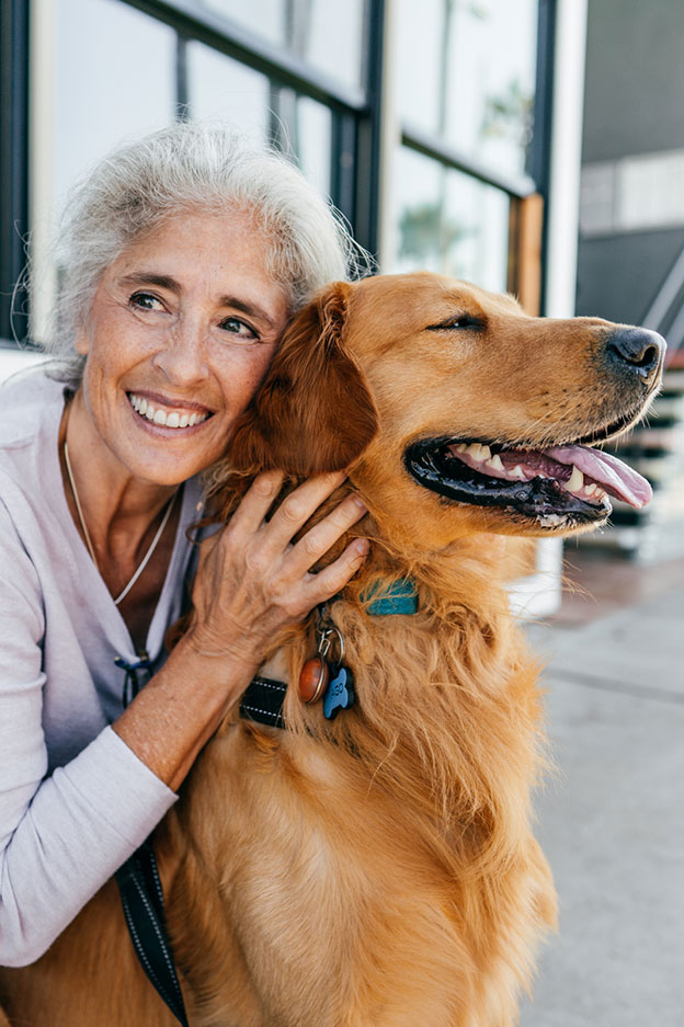 mujer mayor abrazando a un perro golden retriever feliz
