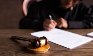 judge signing paper next to wooden gavel