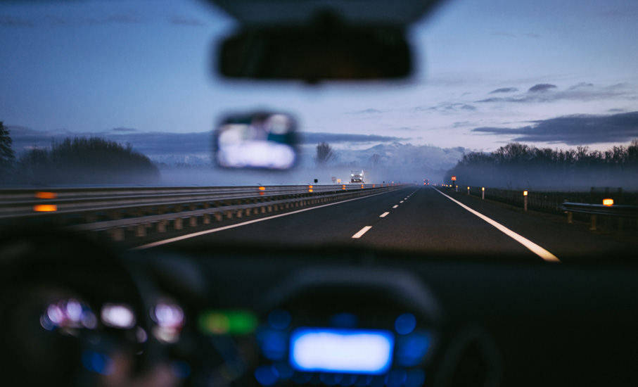 looking out front windshield of car driving on highway at dusk