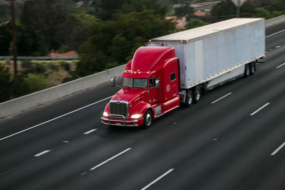 red and white tractor trailer truck driving on highway