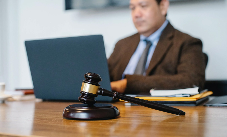 judge sitting at desk with laptop and gavel