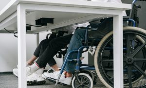 close up of two people sitting at desk, one in a wheelchair