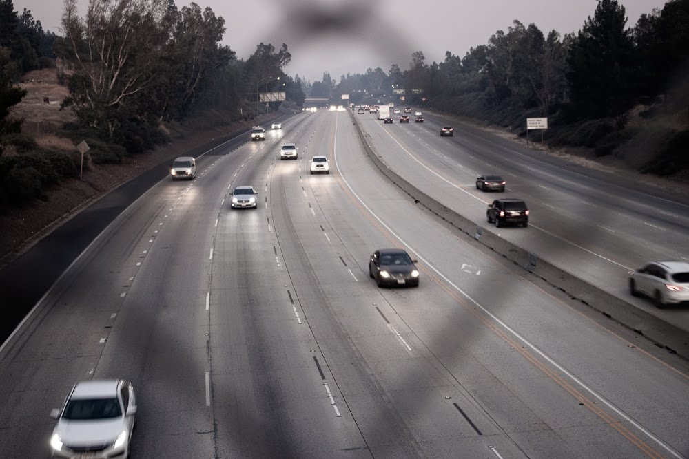 cars driving on highway at night seen through chain-link fence