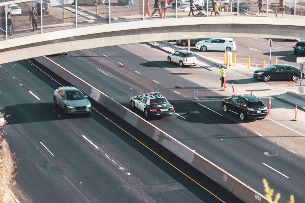 cars and police car driving on highway under a pedestrian bridge