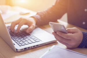 Man typing on laptop and calling a personal injury lawyer.