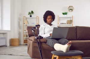 black woman in a foot cast on her laptop